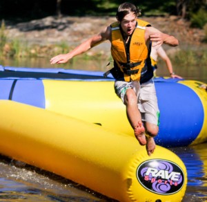 Big inflated aqua tramp on the lake, boy jumping off