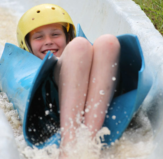 Kid racing down the waterslide on a blue mat